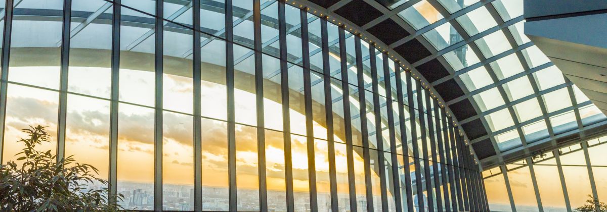Sky Garden London: Indoor garden with large glass windows showing a city view at sunset, filled with people enjoying the space.